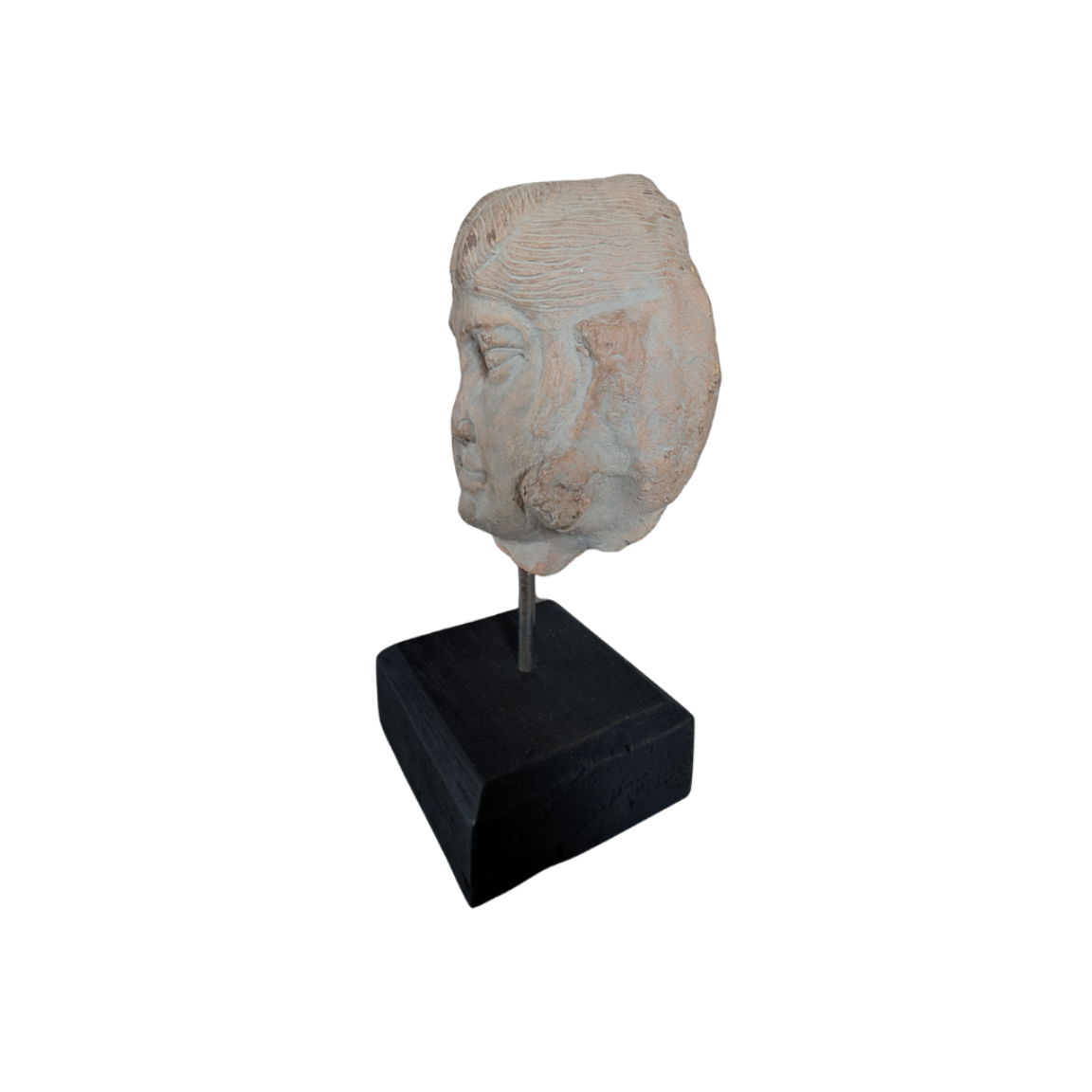 Stone sculpture of a face on a black stand against a white background