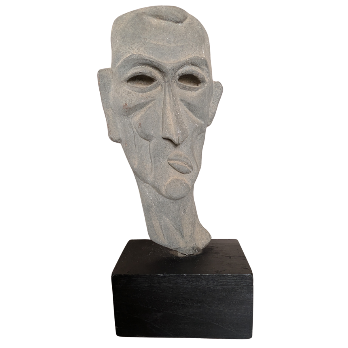 Stone sculpture of a face on a black base against a white background