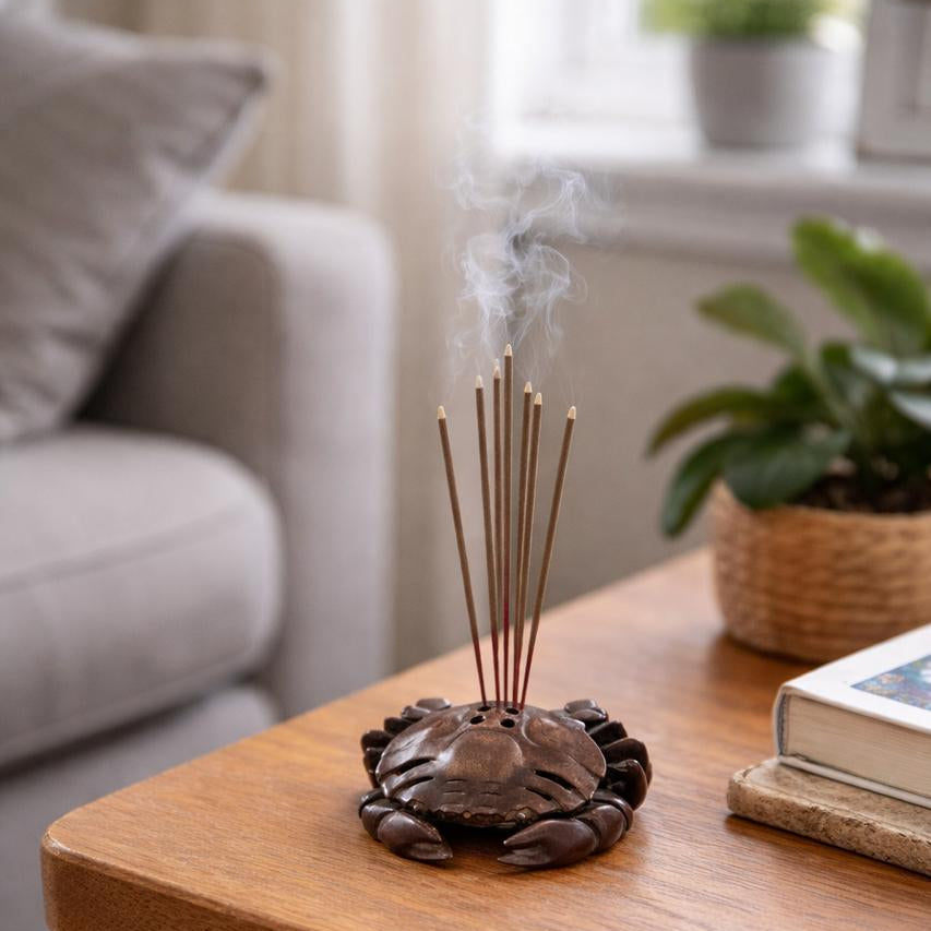 Incense stick holder with burning incense on a wooden table in a living room.